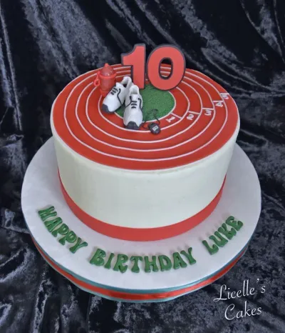 White 1-tier cake with a red running track top, running shoe toppers, and a number 10 printout. White 1-tier cake with a red running track top, running shoe toppers, and a number 10 printout.