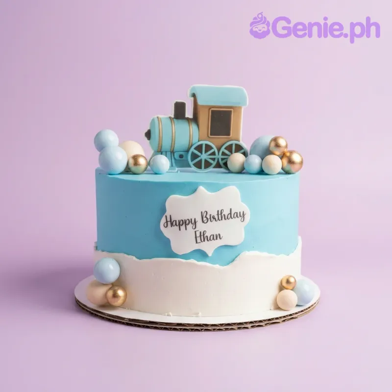 A light blue and white 1-tier Train cake, featuring a blue steam engine topper, decorative spheres, and 'Happy Birthday Ethan' text. A light blue and white 1-tier Train cake, featuring a blue steam engine topper, decorative spheres, and 'Happy Birthday Ethan' text.