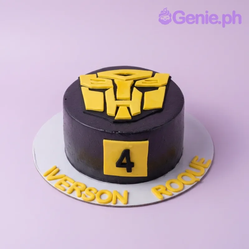 A black Transformers themed 1 Tier cake with a large yellow Autobot logo, a yellow number 4, and yellow text. A black Transformers themed 1 Tier cake with a large yellow Autobot logo, a yellow number 4, and yellow text.