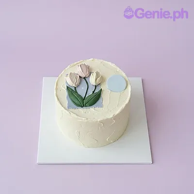 White 1-tier cake with three pink and white tulip toppers and a blue square accent White 1-tier cake with three pink and white tulip toppers and a blue square accent