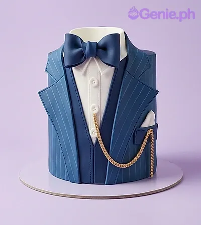 Blue tuxedo fondant cake with a navy bow tie, white shirt collar, and a gold chain detail. Blue tuxedo fondant cake with a navy bow tie, white shirt collar, and a gold chain detail.