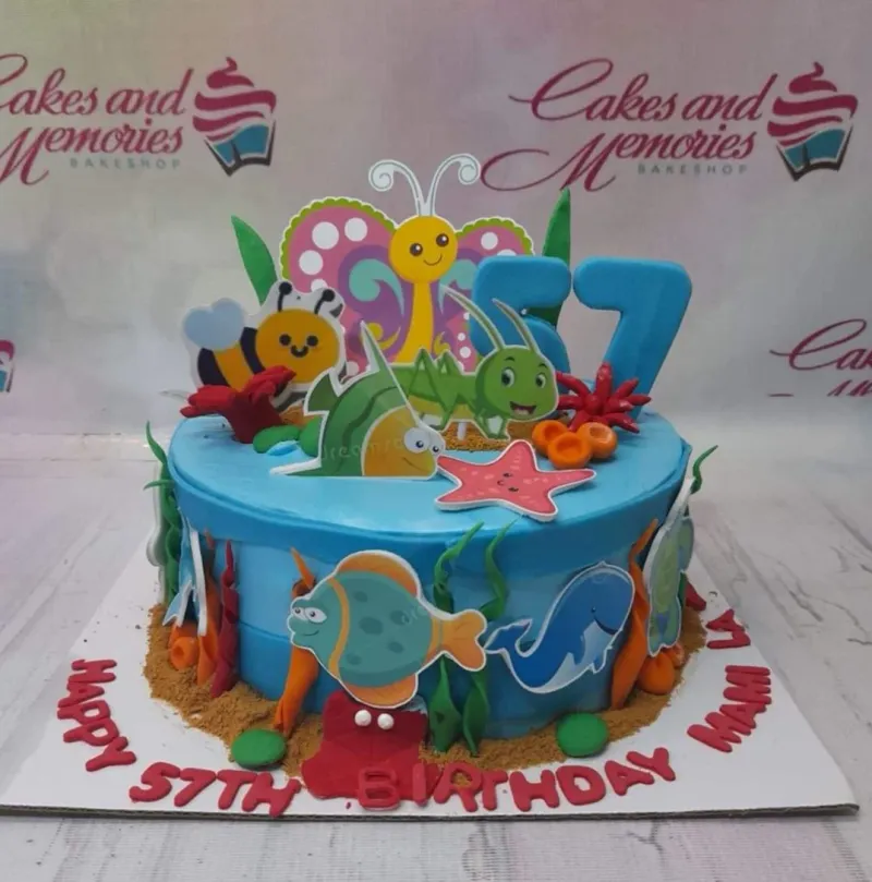 Blue underwater themed birthday cake with colorful sea creature printouts and a large blue number 57 topper. Blue underwater themed birthday cake with colorful sea creature printouts and a large blue number 57 topper.