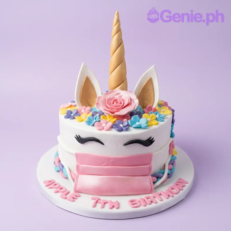 A white 1 Tier cake themed around Unicorn, featuring a gold horn, ears, pink face mask, and colorful fondant flowers. A white 1 Tier cake themed around Unicorn, featuring a gold horn, ears, pink face mask, and colorful fondant flowers.