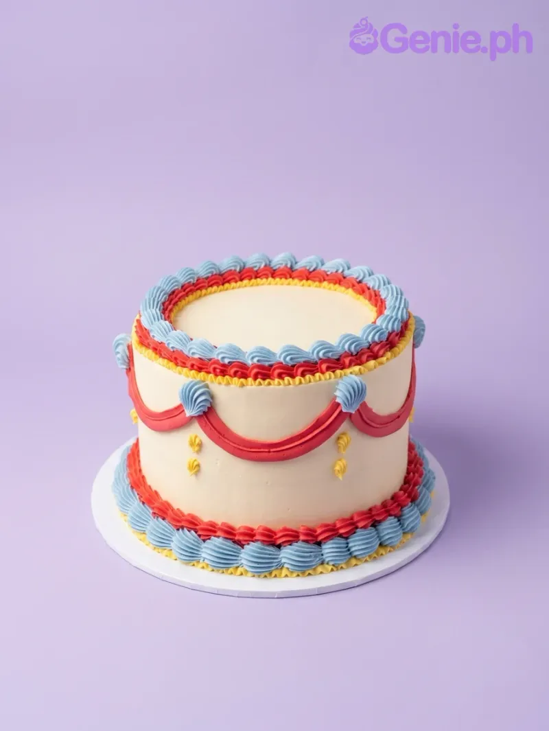 An ivory 1-tier Vintage Piped cake with red, blue, and yellow piped borders, red swags, blue shell accents, and yellow dots. An ivory 1-tier Vintage Piped cake with red, blue, and yellow piped borders, red swags, blue shell accents, and yellow dots.