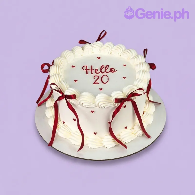 A white and red 1-tier cake themed Vintage Red Ribbon, featuring dark red bows, piped white borders, and 'Hello 20' text. A white and red 1-tier cake themed Vintage Red Ribbon, featuring dark red bows, piped white borders, and 'Hello 20' text.