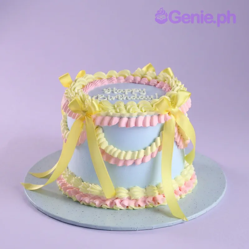 Light blue 1-tier cake with smooth soft icing, yellow satin ribbons, and piped pink and yellow shell borders