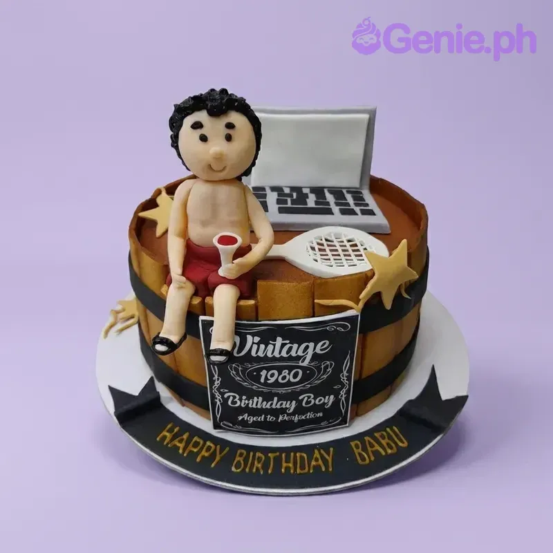 A brown and black 1 Tier Fondant cake themed around a Vintage Whiskey Barrel, featuring a man figure, laptop, tennis racket, and gold stars.