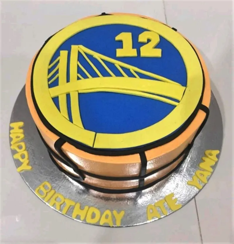 Golden State Warriors basketball themed cake with blue and yellow logo and black basketball lines on orange icing. Golden State Warriors basketball themed cake with blue and yellow logo and black basketball lines on orange icing.