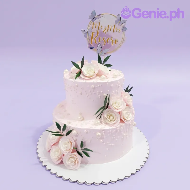 A light pink 2-tier wedding cake with a 'Mr & Mrs Rosero' topper, white gumpaste roses, and edible pearls. A light pink 2-tier wedding cake with a 'Mr & Mrs Rosero' topper, white gumpaste roses, and edible pearls.
