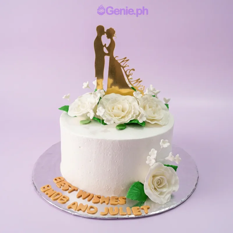 A white 1-tier cake themed around Wedding Silhouette, featuring a gold silhouette couple topper and white gumpaste roses with green leaves. A white 1-tier cake themed around Wedding Silhouette, featuring a gold silhouette couple topper and white gumpaste roses with green leaves.
