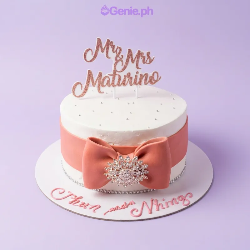 A white 1-tier wedding cake, featuring a rose gold glitter Mr & Mrs Maturino topper and a peach fondant bow with a rhinestone brooch. A white 1-tier wedding cake, featuring a rose gold glitter Mr & Mrs Maturino topper and a peach fondant bow with a rhinestone brooch.