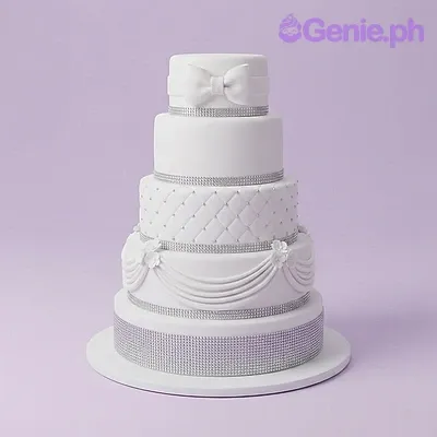 White 3-tier fondant wedding cake with silver ribbon bands, quilted texture, and a fondant bow topper White 3-tier fondant wedding cake with silver ribbon bands, quilted texture, and a fondant bow topper