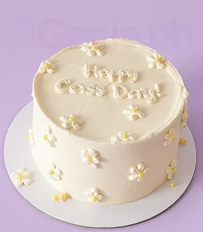 A white and yellow 1 Tier minimalist daisy cake, featuring piped daisies with yellow centers and 'Happy Cass Day!' text. A white and yellow 1 Tier minimalist daisy cake, featuring piped daisies with yellow centers and 'Happy Cass Day!' text.