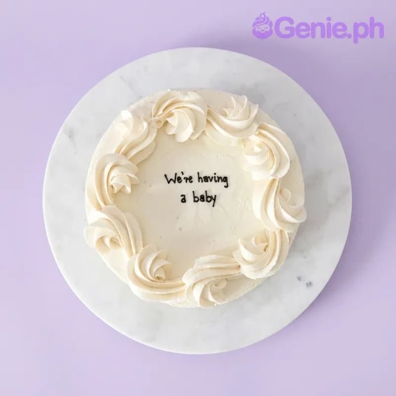 A white 1-tier cake themed around a baby announcement, featuring large white icing rosettes and a black icing message. A white 1-tier cake themed around a baby announcement, featuring large white icing rosettes and a black icing message.