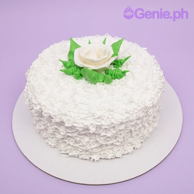 A white 1 Tier cake themed White Rose Minimalist, featuring a large white gumpaste rose, green leaves, and white icing swirls. A white 1 Tier cake themed White Rose Minimalist, featuring a large white gumpaste rose, green leaves, and white icing swirls.