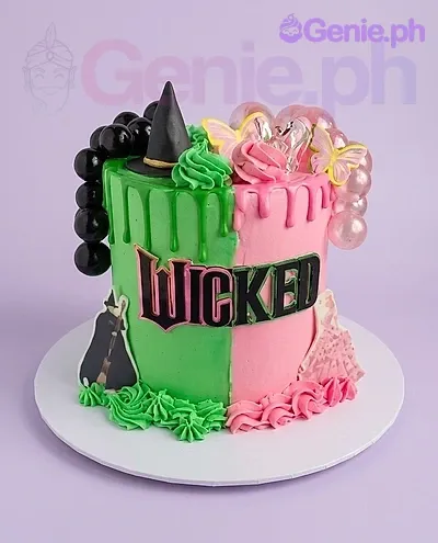 A green and pink 1-tier Wicked Musical cake, featuring a Wicked logo, black witch hat, and decorative bubbles. A green and pink 1-tier Wicked Musical cake, featuring a Wicked logo, black witch hat, and decorative bubbles.