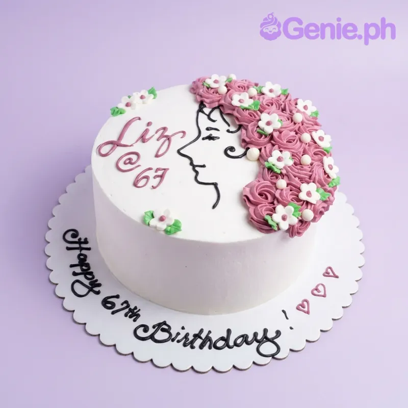 A white 1-tier cake with a piped icing silhouette of a woman, pink floral hair, white flowers, green leaves, and birthday messages. A white 1-tier cake with a piped icing silhouette of a woman, pink floral hair, white flowers, green leaves, and birthday messages.