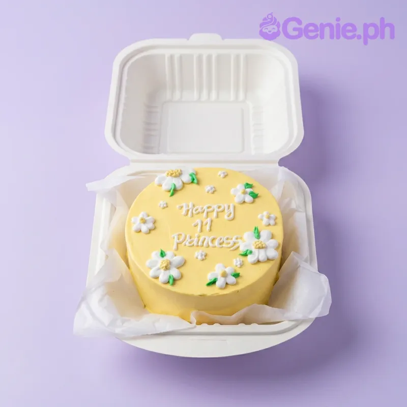 A yellow and white bento cake themed with yellow daisies, featuring piped white icing daisies and 'Happy 11 Princess' text. A yellow and white bento cake themed with yellow daisies, featuring piped white icing daisies and 'Happy 11 Princess' text.