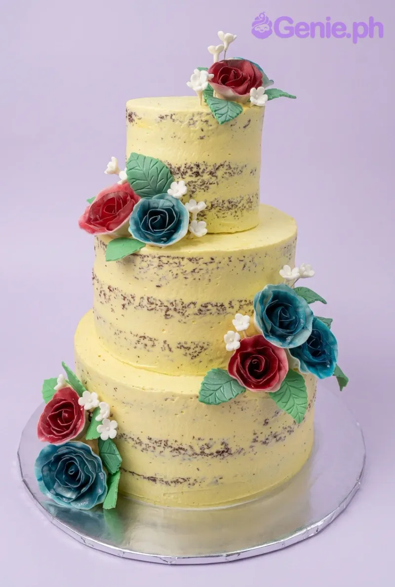 A yellow semi-naked 3-tier Yellow Floral cake, featuring red and teal gumpaste roses, green leaves, and white filler flowers. A yellow semi-naked 3-tier Yellow Floral cake, featuring red and teal gumpaste roses, green leaves, and white filler flowers.