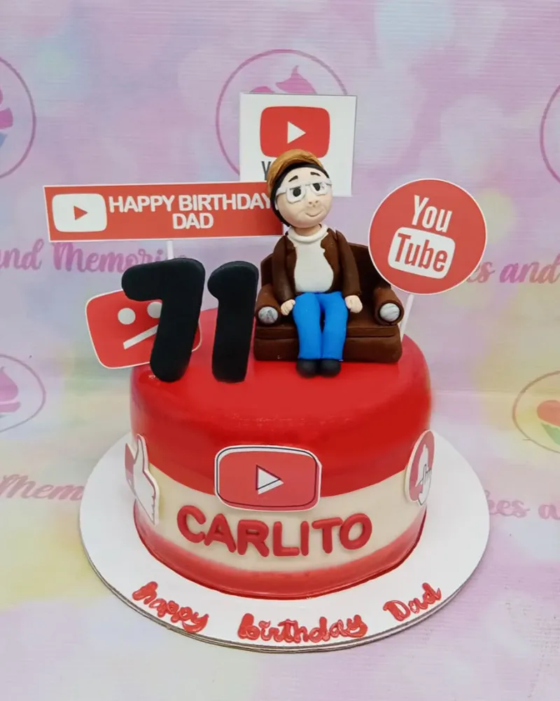 A red and white 1 Tier Fondant cake themed around YouTube Birthday, featuring a man on a sofa figurine, number 71, and YouTube logos. A red and white 1 Tier Fondant cake themed around YouTube Birthday, featuring a man on a sofa figurine, number 71, and YouTube logos.