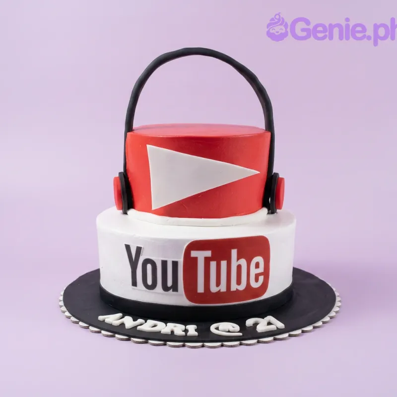 A red and white 2 Tier Fondant cake themed around YouTube, featuring black headphones, a white play button, and the YouTube logo. A red and white 2 Tier Fondant cake themed around YouTube, featuring black headphones, a white play button, and the YouTube logo.