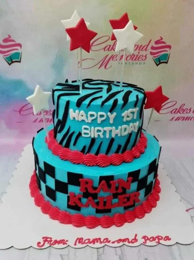 Two-tier blue birthday cake with zebra stripes, checkered patterns, and red and white star toppers. Two-tier blue birthday cake with zebra stripes, checkered patterns, and red and white star toppers.