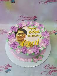 A photo of an Elegant Edible Photo themed cake. It is a Light Pink 1 Tier cake decorated with an edible photo of a woman, 'Happy 60th Birthday Cecil' message, and piped flowers and leaves.