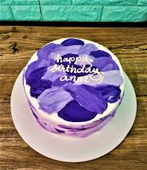 A photo of an Eliana themed cake. It is a white 1-tier round cake decorated with pink brushstroke icing on top, blue brushstroke icing on the sides, and the message 'happy birthday eliana!' in white script.