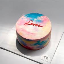 A photo of a Lover themed cake. It is a pink and blue 1 Tier cake decorated with a red 'Lover' message, pink drips, black piped borders, and a sky-like cloud design. A photo of a Lover themed cake. It is a pink and blue 1 Tier cake decorated with a red 'Lover' message, pink drips, black piped borders, and a sky-like cloud design.