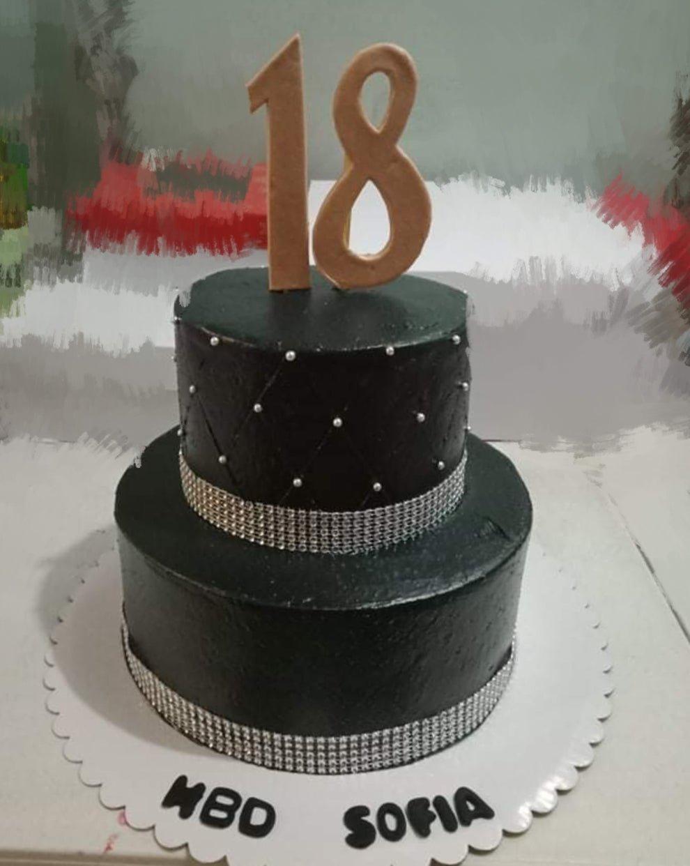 Elegant black 2-tier 18th birthday cake with silver quilted pattern, edible pearls, and large gold number 18 topper.