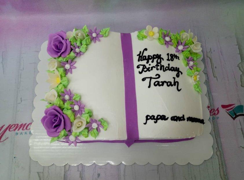 Rectangle book-shaped birthday cake with white icing, purple fondant roses, and green icing leaves for an 18th birthday celebration.