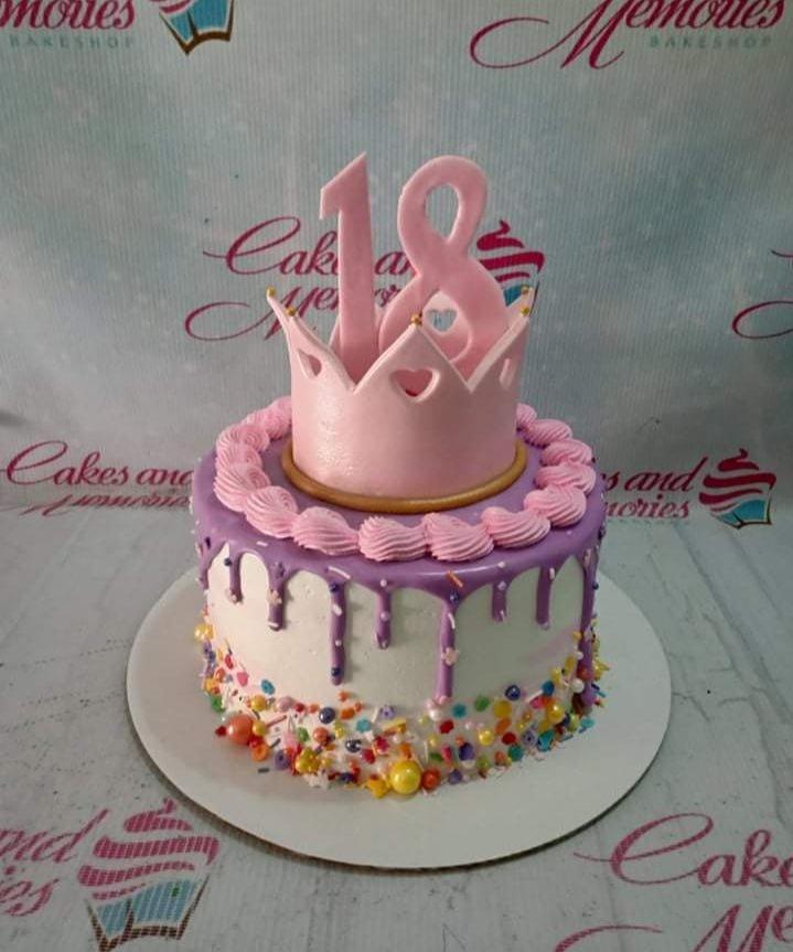 Purple and white 18th birthday cake with a pink crown and number 18 topper, purple drip, and colorful sprinkles.