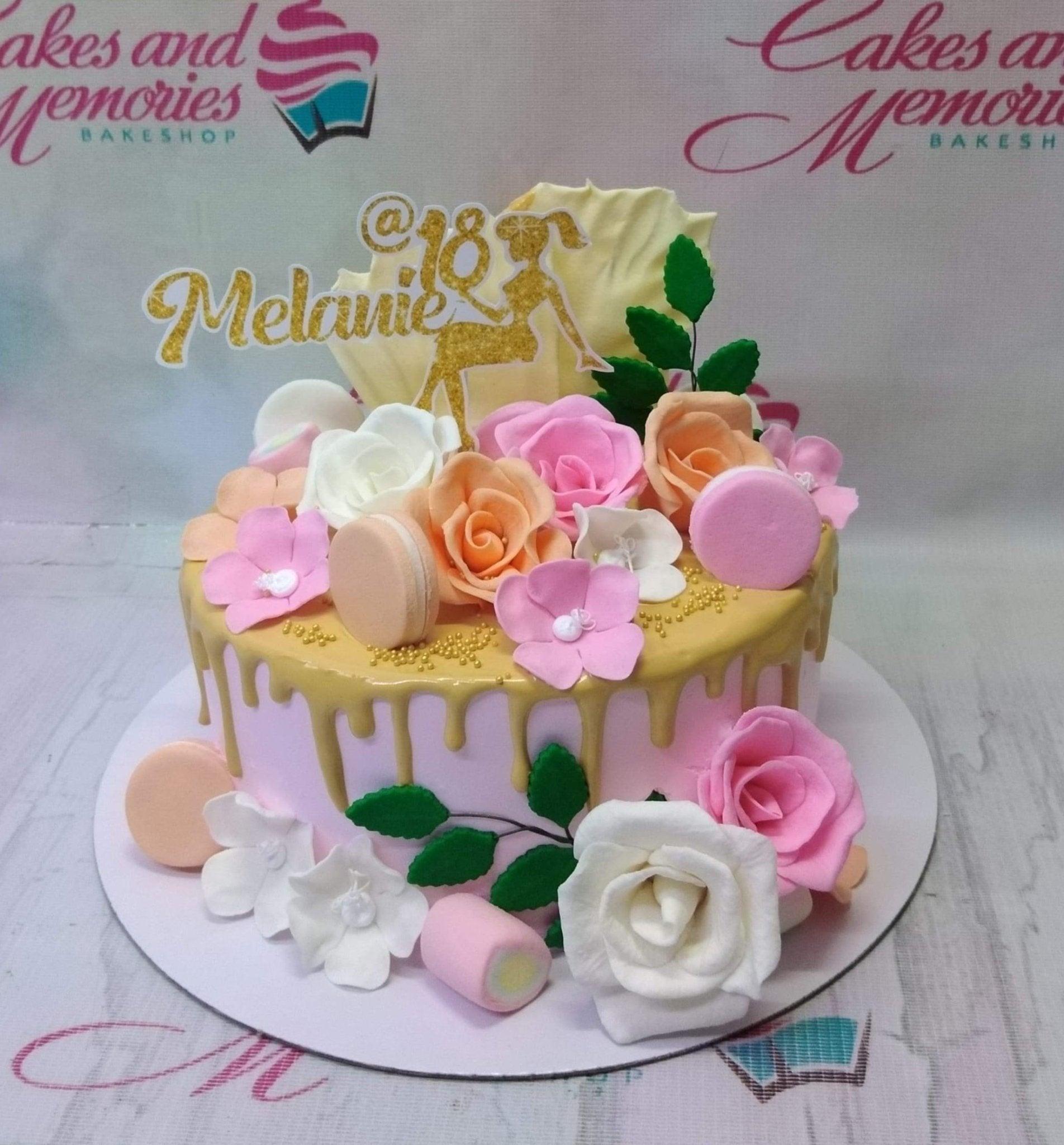 Pink 18th birthday cake with gold drip, pink and white edible roses, macarons, and a gold glitter Melanie topper.