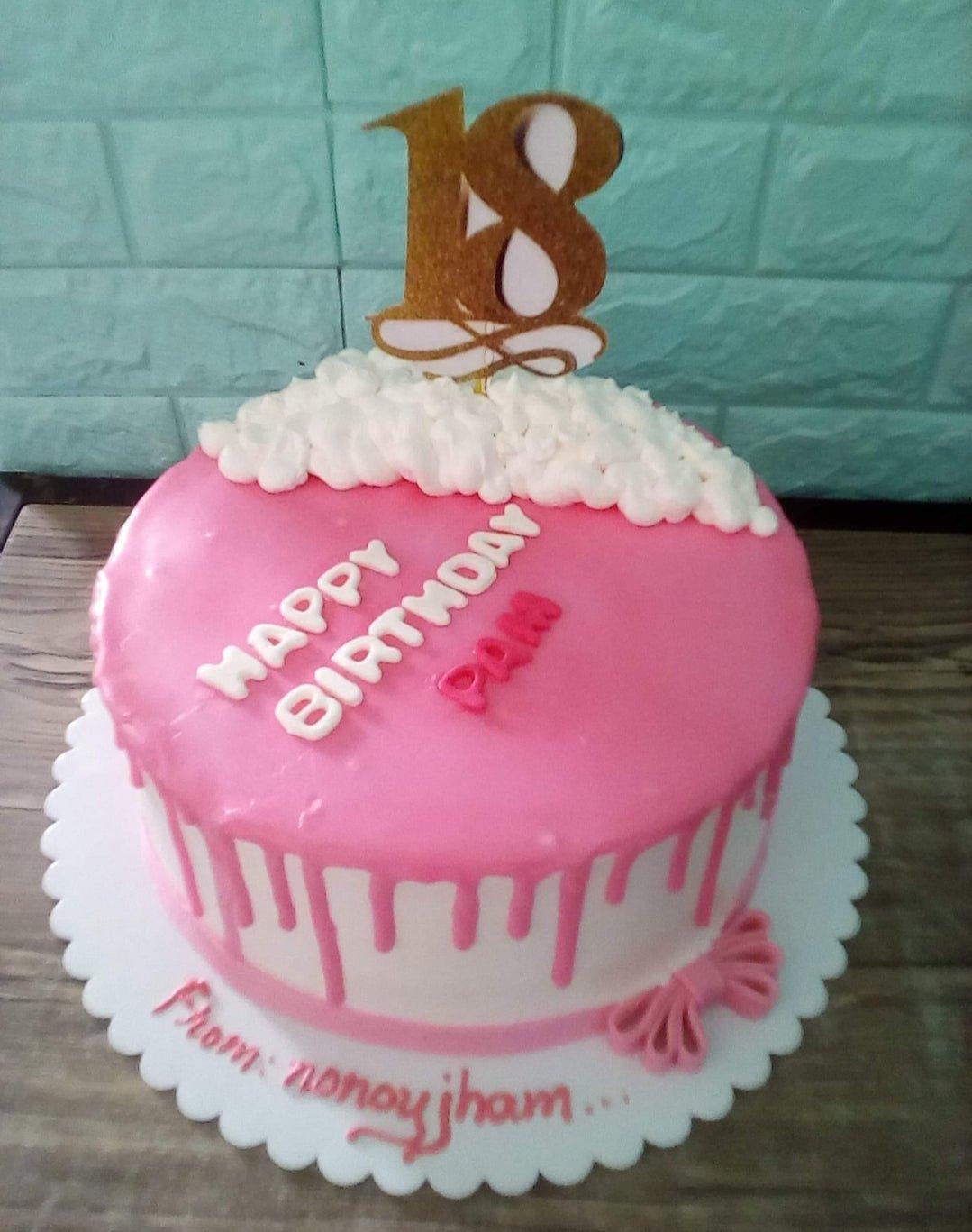 Pink and white 18th birthday cake with pink drip, white icing clouds, and a gold glitter number 18 topper.