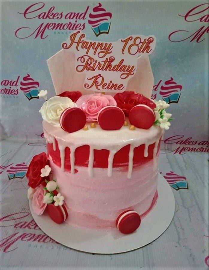 Pink and red 18th birthday cake with white drip, macarons, and roses