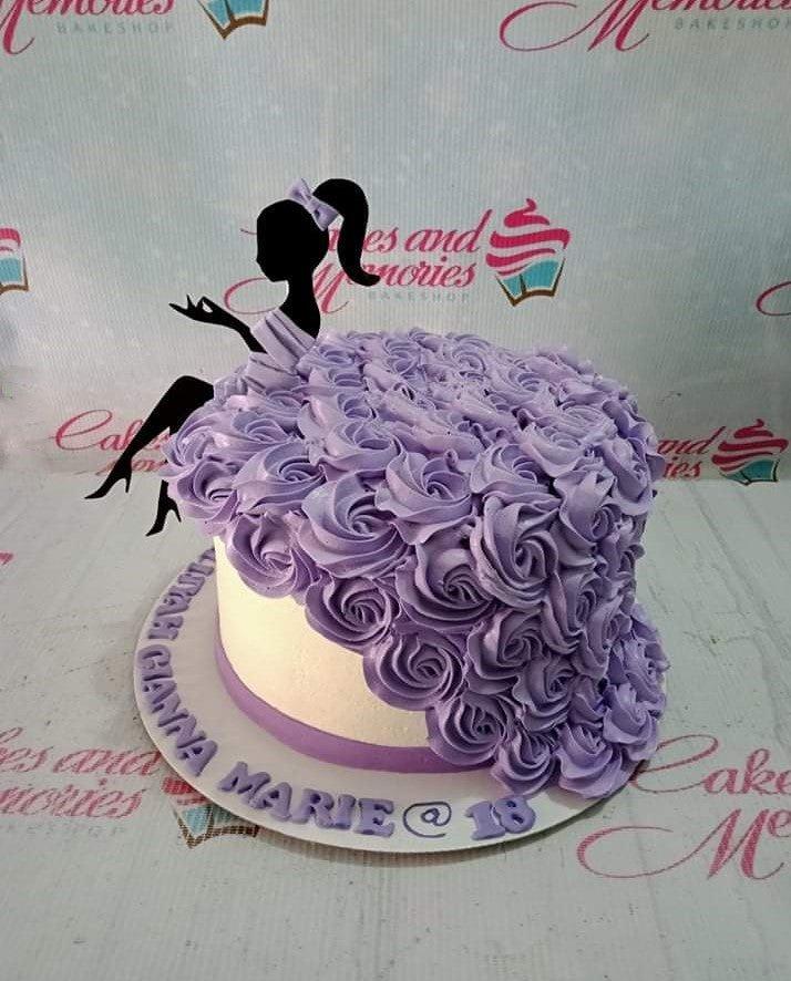 Elegant 18th birthday cake with a black silhouette topper and a flowing purple icing rosette dress design on a white base.