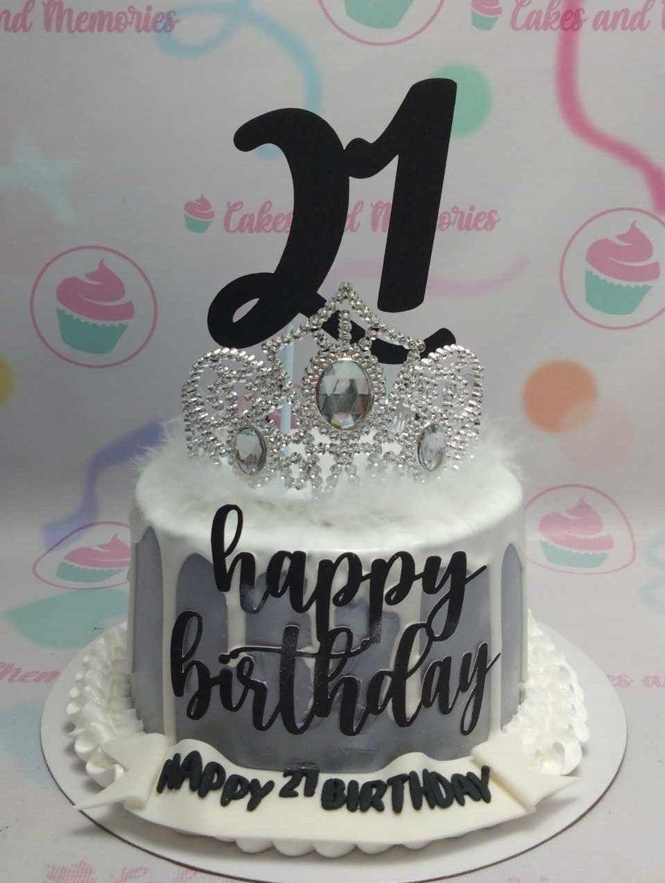 White and gray marble effect birthday cake with a silver rhinestone tiara, black number 21 topper, and a Happy Birthday message.