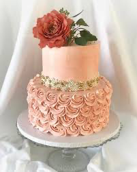 Elegant 2-tier peach cake with a large coral rose topper, gold floral band, and intricate peach icing rosettes on the bottom tier.