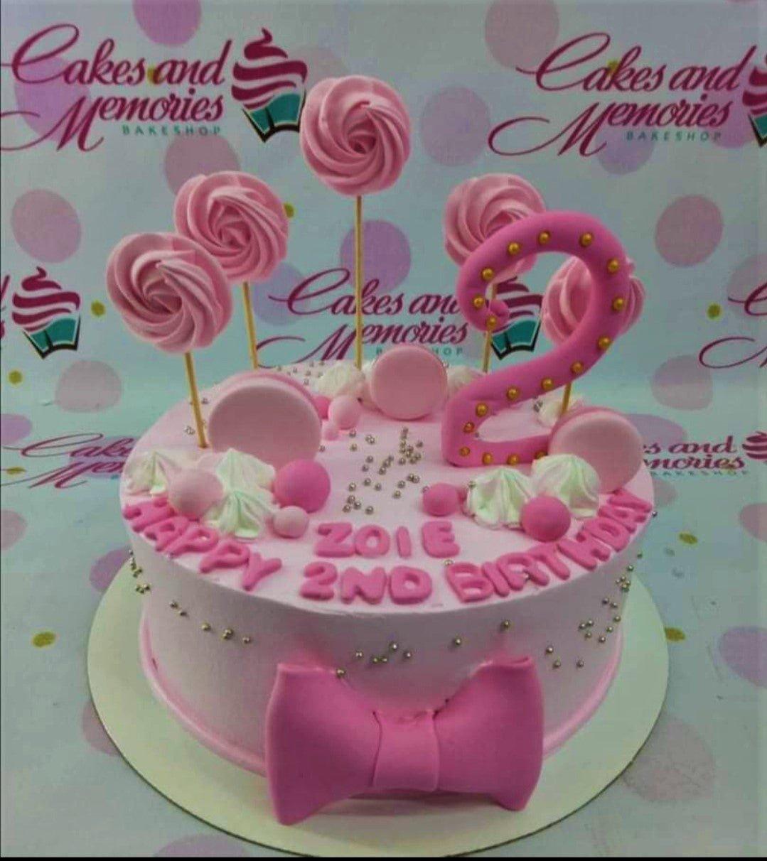 Pink 1-tier birthday cake with a large pink number 2 topper, pink meringue pops, and a large pink fondant bow.