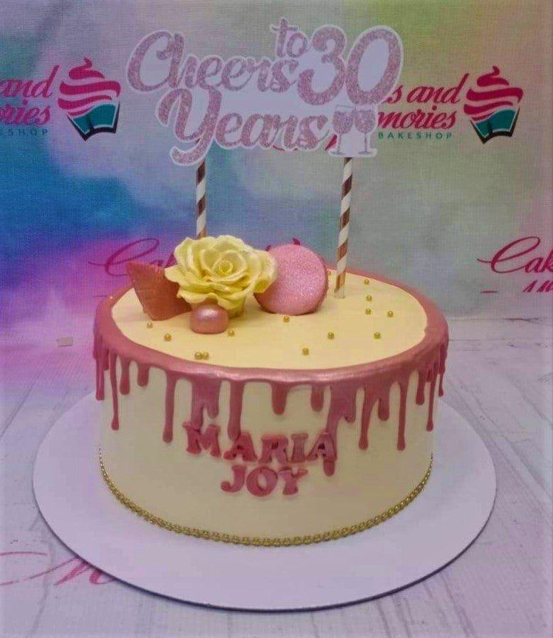 Cream colored 1-tier cake with rose gold drip, a yellow rose, pink macaron, and a Cheers to 30 Years topper.