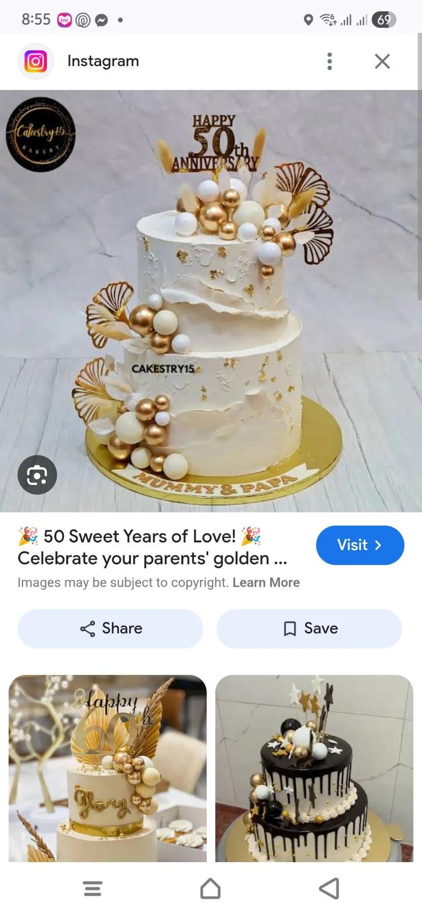 Elegant 2-tier white anniversary cake with gold and white spheres, dried leaves, and a gold 50th anniversary topper.