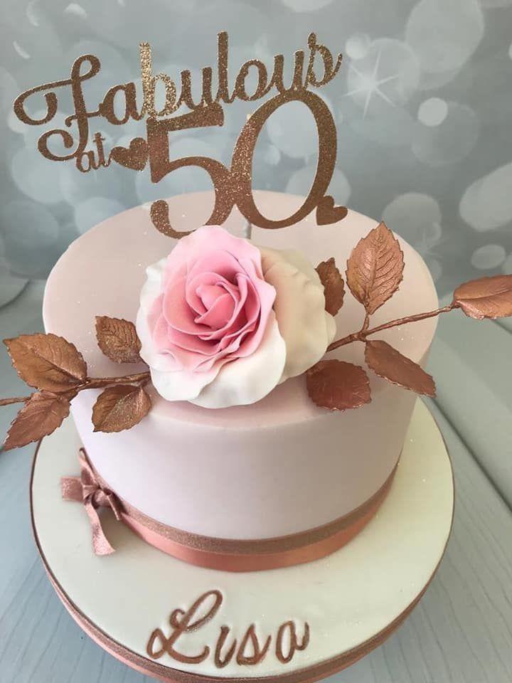 Elegant light pink fondant cake for a 50th birthday featuring a large pink sugar rose and a gold glitter Fabulous at 50 topper.