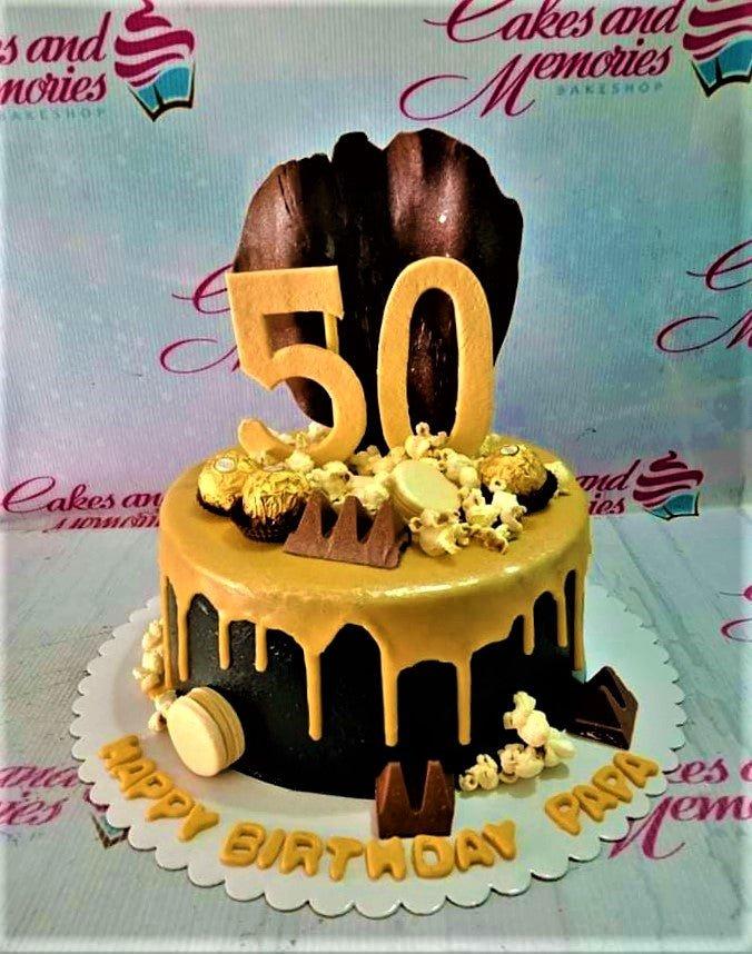 Black 50th birthday cake with gold drip, Ferrero Rocher, popcorn, and chocolate accents for Papa.