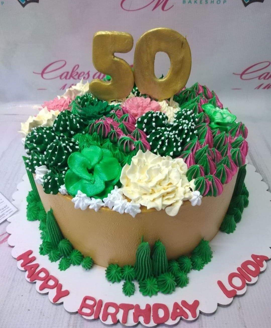 Gold 50th birthday cake with lush green and pink succulent-style icing rosettes and a large gold number 50 topper.