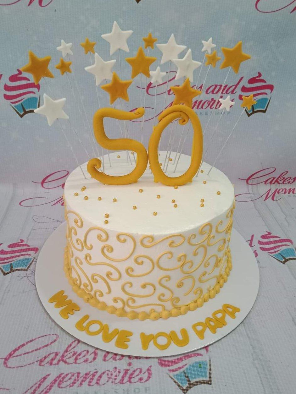White 1-tier birthday cake for a 50th birthday featuring gold fondant swirls, gold number 50 topper, and white and gold stars on wires.