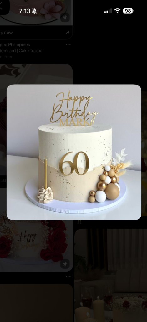 Elegant cream 60th birthday cake with gold splatter, gold acrylic topper, and a cluster of gold, white, and tan decorative balls.