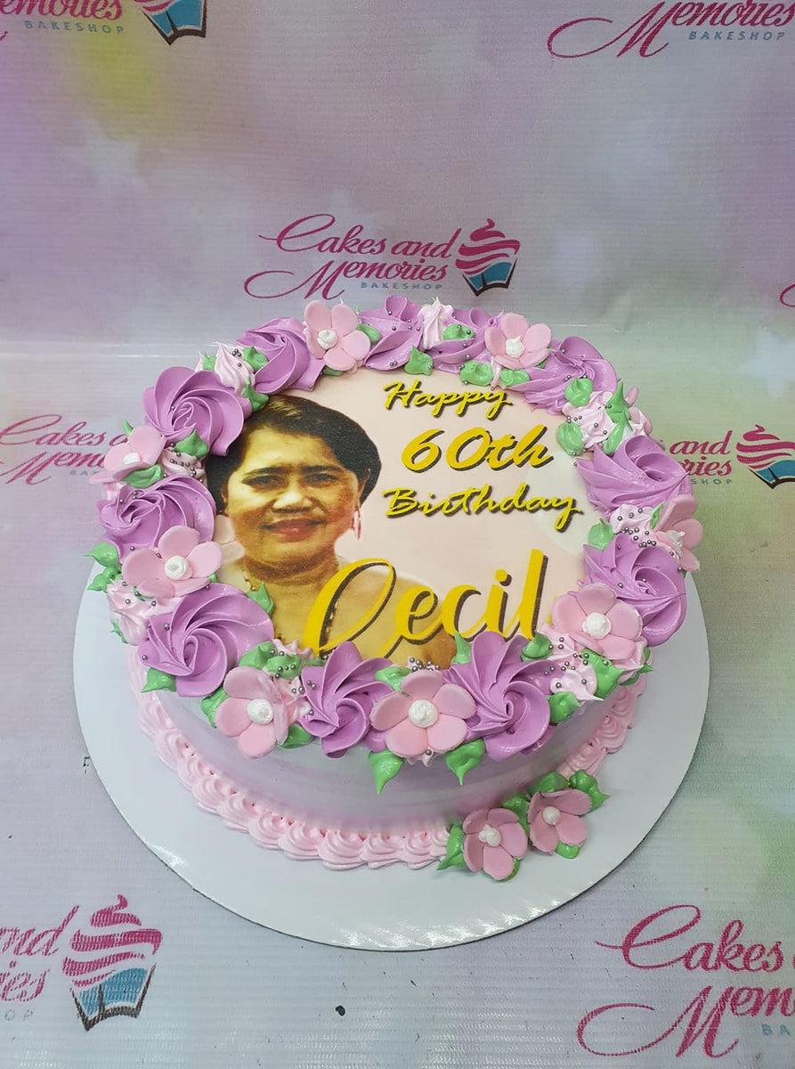 Pink and purple 60th birthday cake with a photo print of a woman, icing rosettes, and pink fondant flowers.