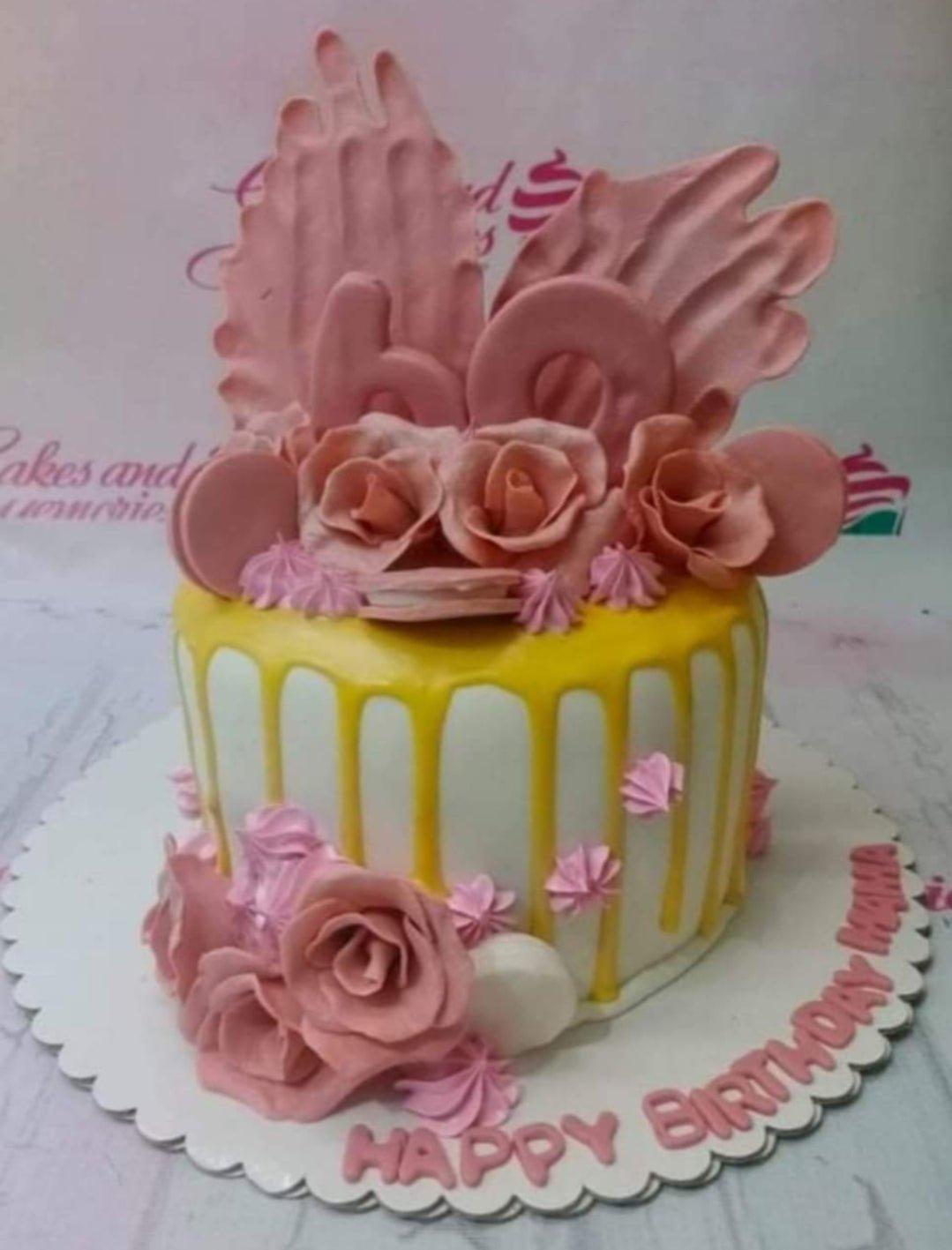 White 1-tier birthday cake with yellow drip, pink icing rosettes, and large pink fondant roses and number 60 topper.