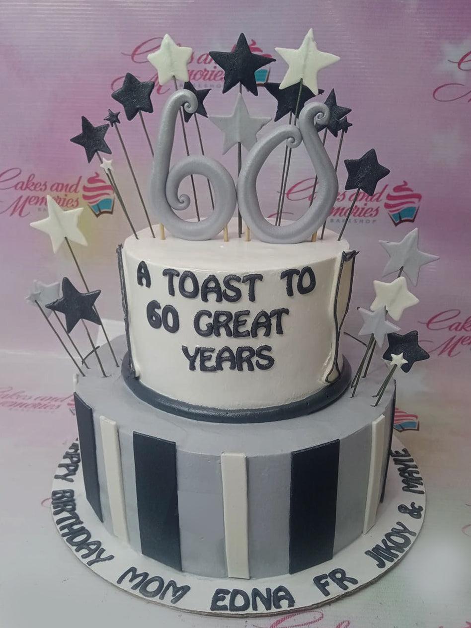 Two-tier 60th birthday cake in gray, white, and black with large silver number 60 topper and star accents.