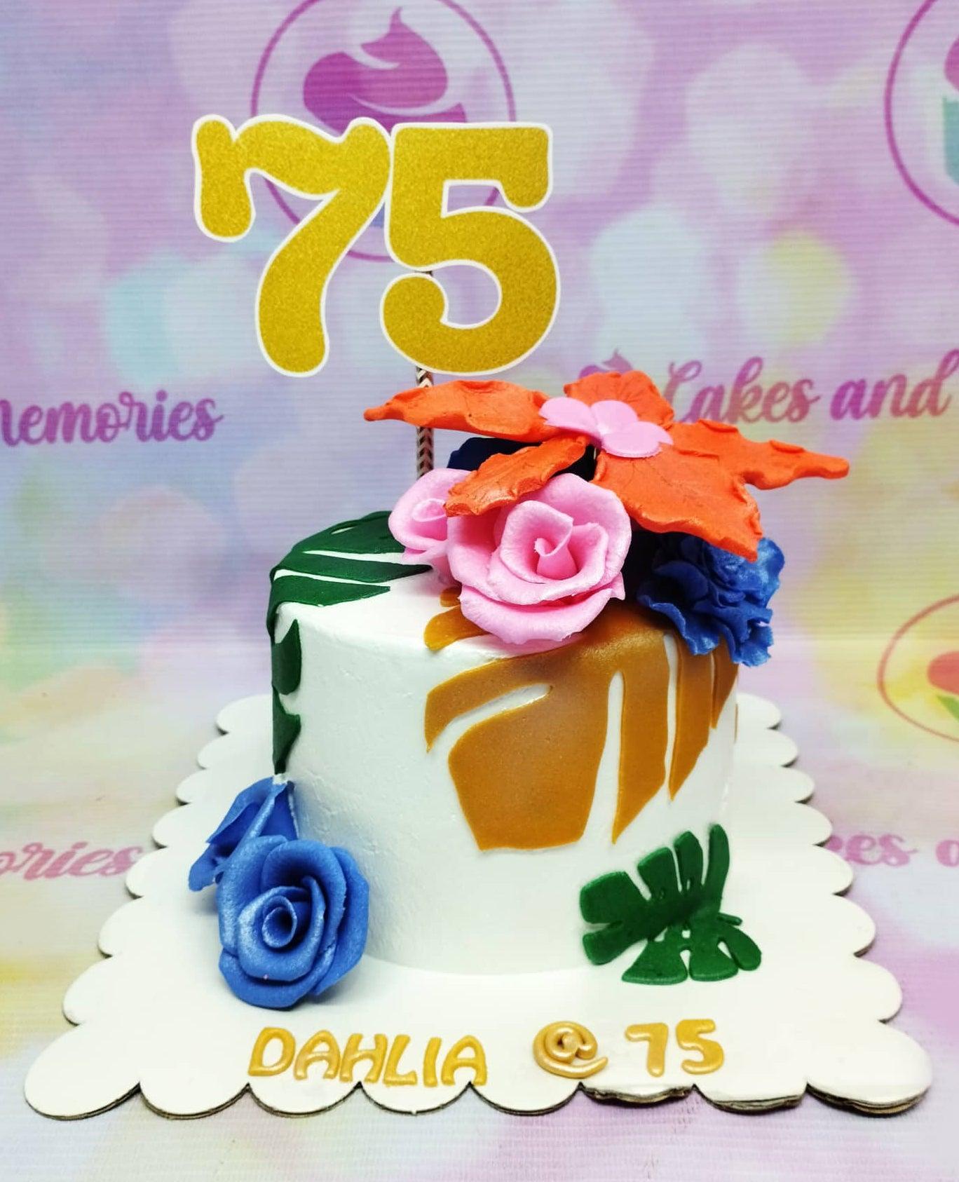 White 1-tier tropical 75th birthday cake with pink and blue gumpaste roses, orange hibiscus, and gold number 75 topper.